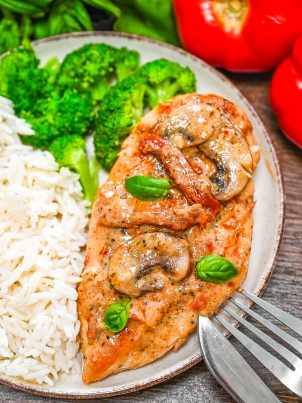 A plate with creamy sun-dried tomato chicken , rice and broccoli