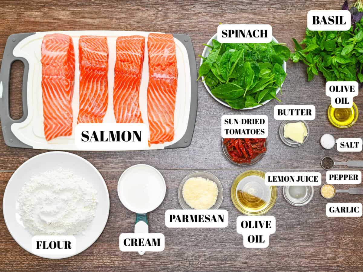 All ingredients necessary to make homemade tuscan salmon  in clear bowls and fish on cutting board.