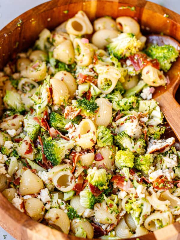 Overhead shot of broccoli pasta salad in a white bowl with toasted feta, bacon, and lemon dressing.