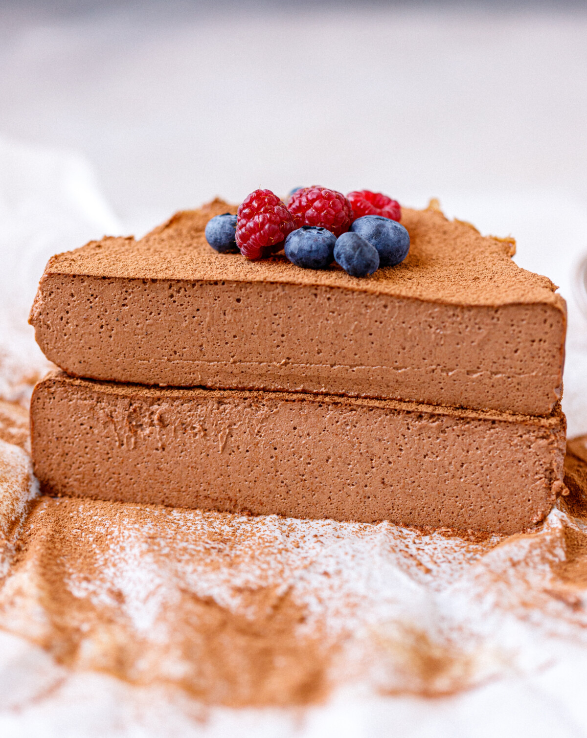 A chocolate cottage cheesecake cut in half, 2 halves stacked on each other.Topped with berries.