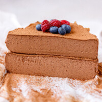 A chocolate cottage cheesecake cut in half, 2 halves stacked on each other.Topped with berries.