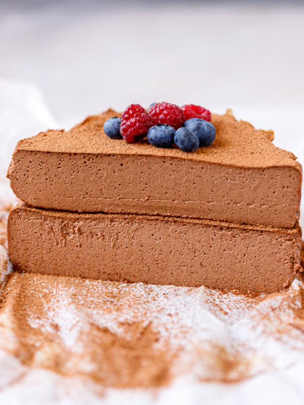 A chocolate cottage cheesecake cut in half, 2 halves stacked on each other.Topped with berries.