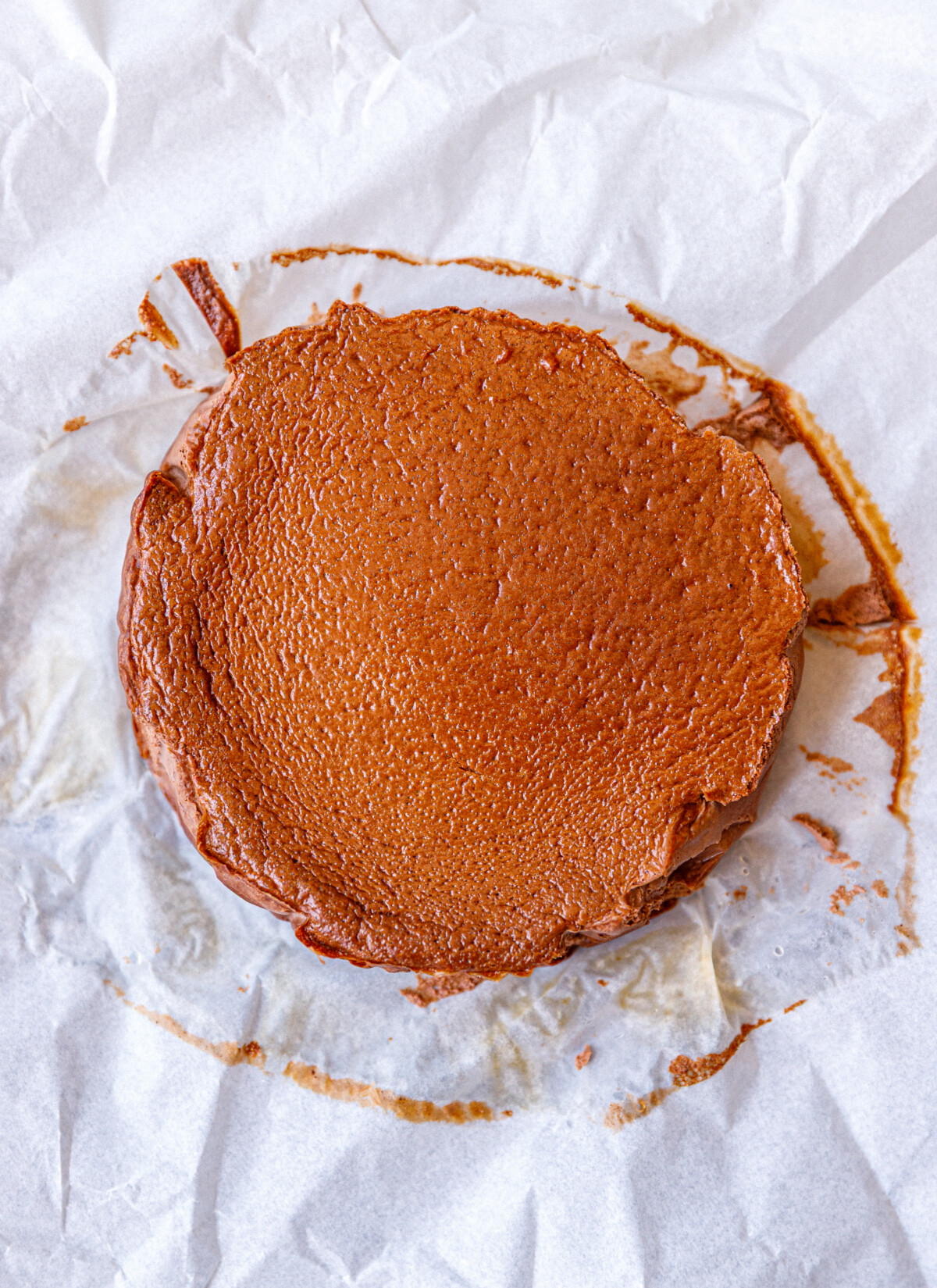 A baked cottage cheese chocolate cheesecake on white parchment paper