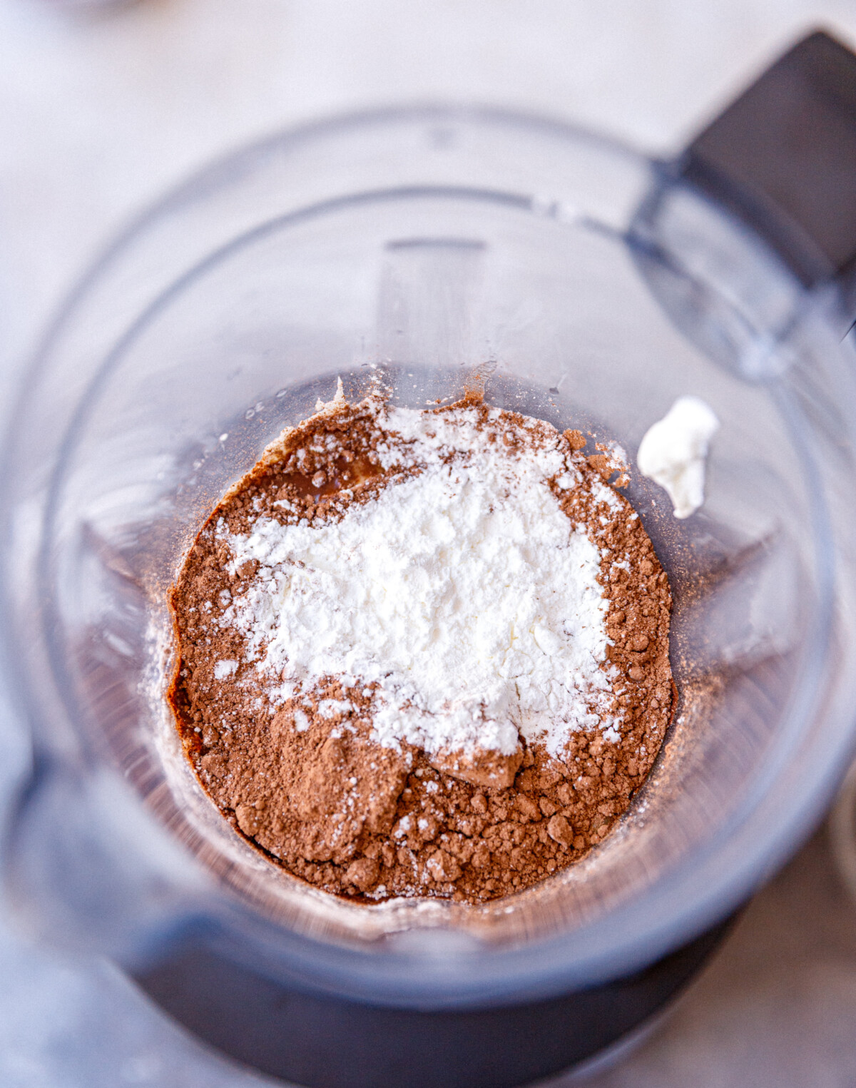 A blender with ingredients for chocolate cottage cheesecake.