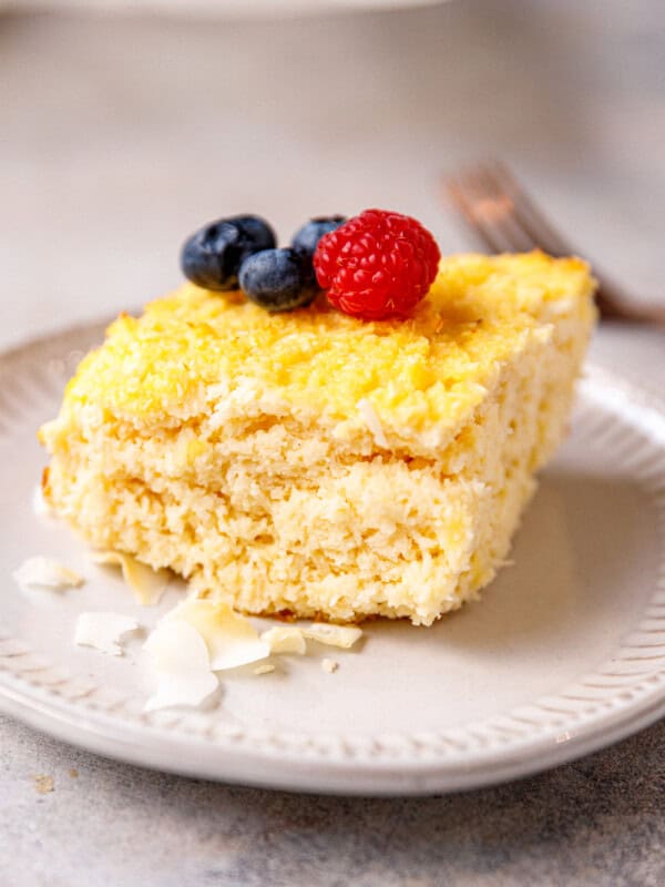 A slice of 6-ingredient yogurt and coconut cake on a plate, topped with berries.