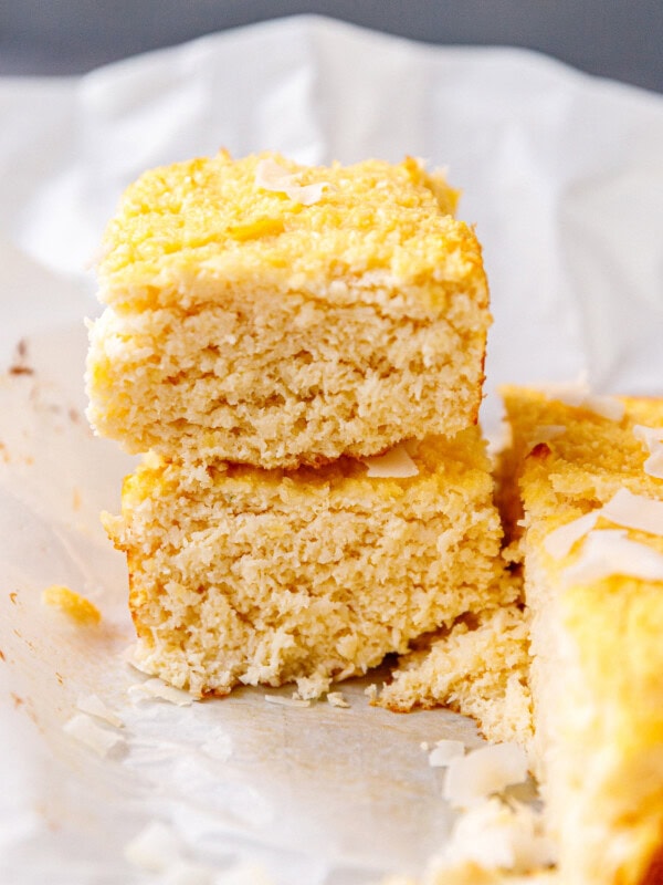 Coconut cake batter spread into a parchment paper-lined square cake pan, ready for baking.