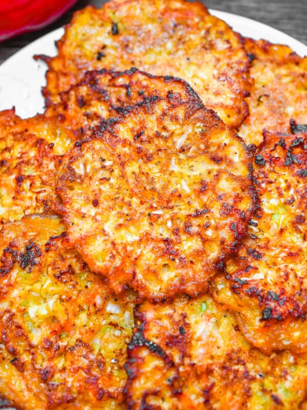 Crispy golden brown cabbage fritters stacked on a plate, made with shredded cabbage, carrot, and onion