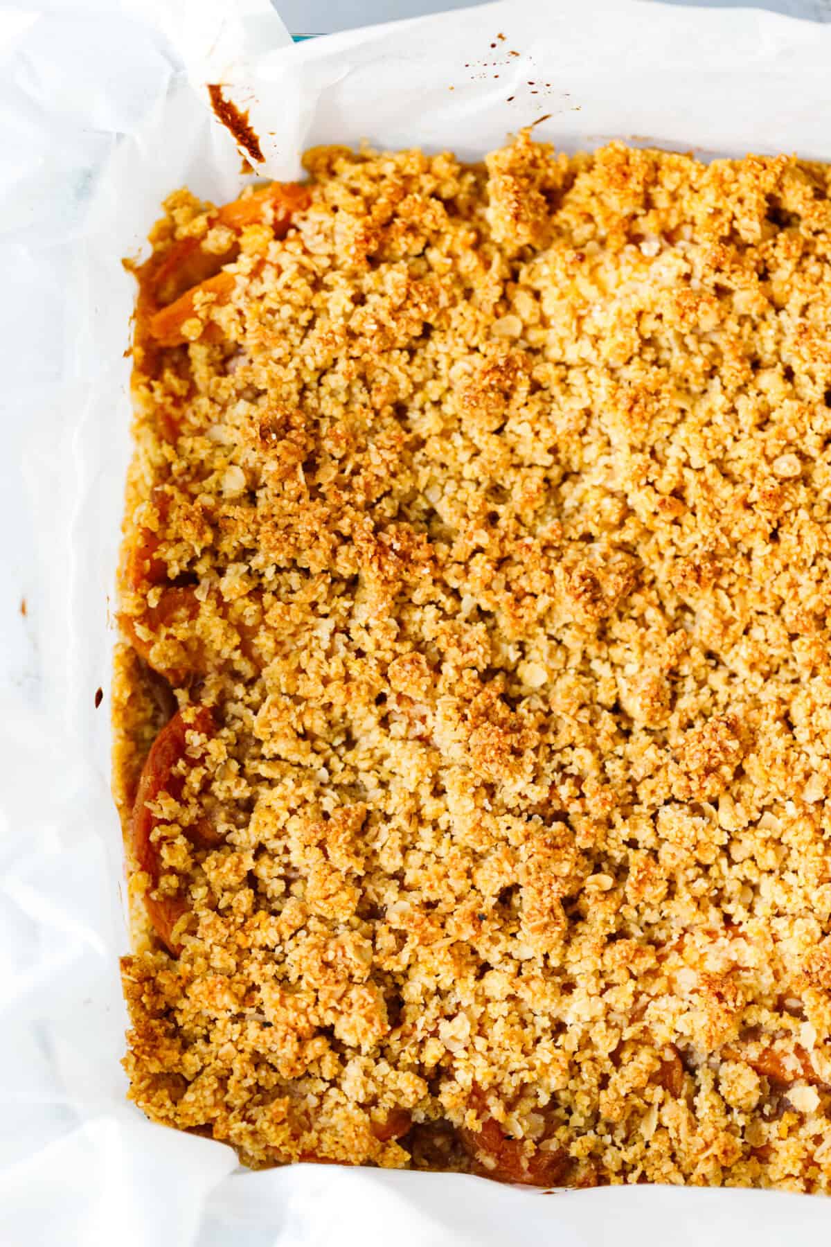 Freshly baked peach bars in a square pan with golden brown crumb topping.