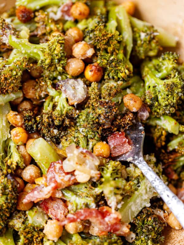 Overhead view of warm roasted broccoli and chickpea salad with bacon and shallots on a white plate.