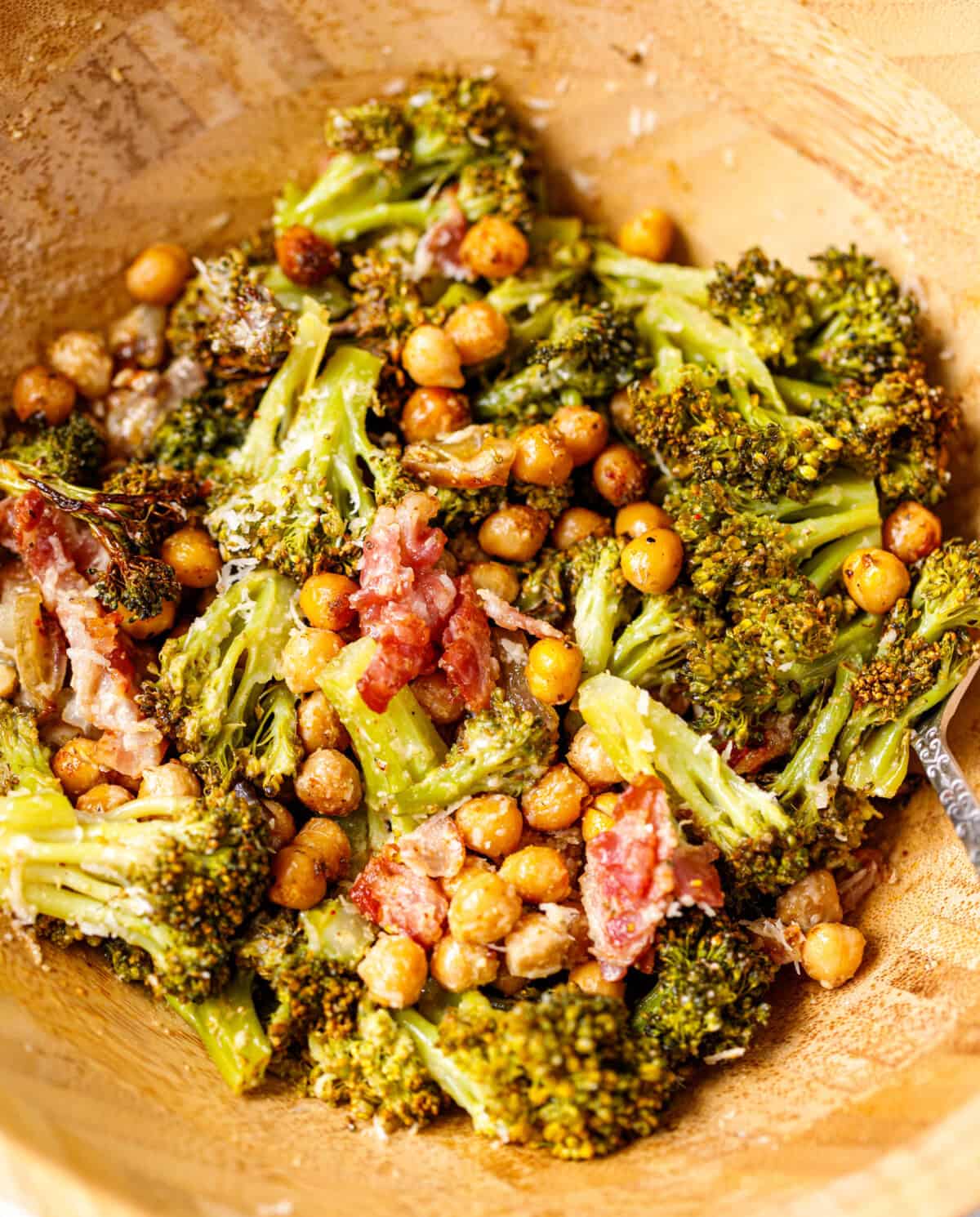Roasted broccoli salad with chickpeas, bacon, and shallots in a serving bowl, drizzled with creamy tahini dressing.