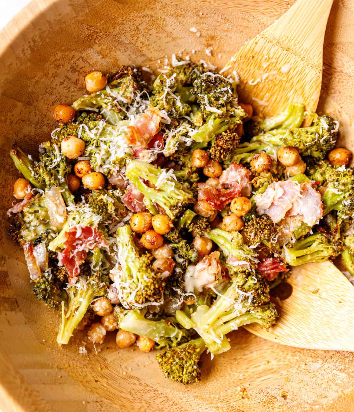 A wooden bowl with warm rosted chickpea and broccoli salad