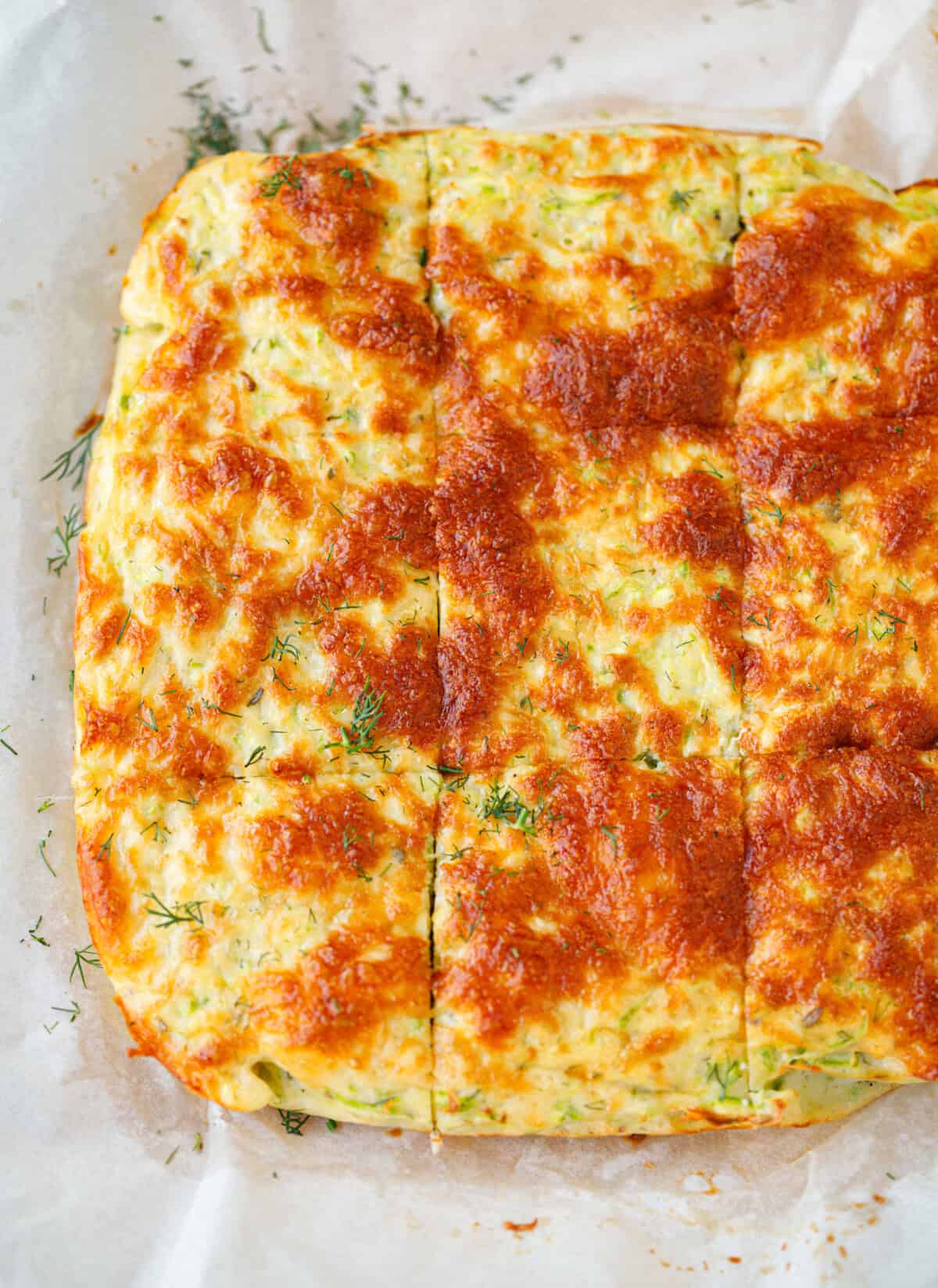 Cheesy zucchini frittata bake in a parchment-lined pan