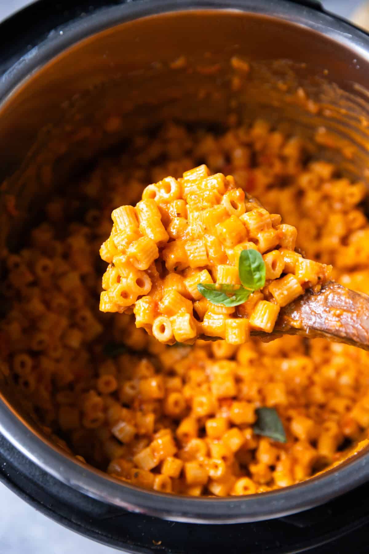 Spoonful of creamy Instant Pot Vodka Pasta lifted from the pot, showing rich tomato cream sauce coating ditalini pasta.