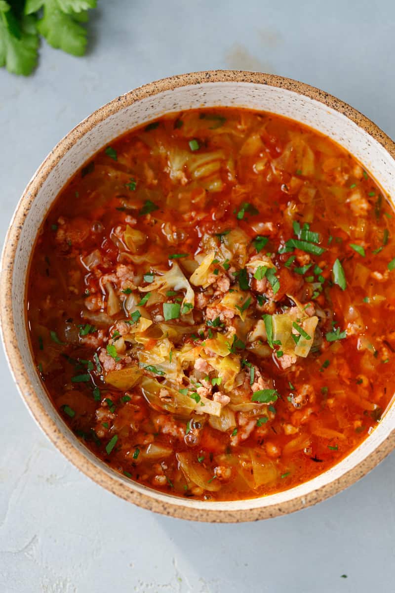 Keto cabbage soup topped with chopped parsley on a bowl.