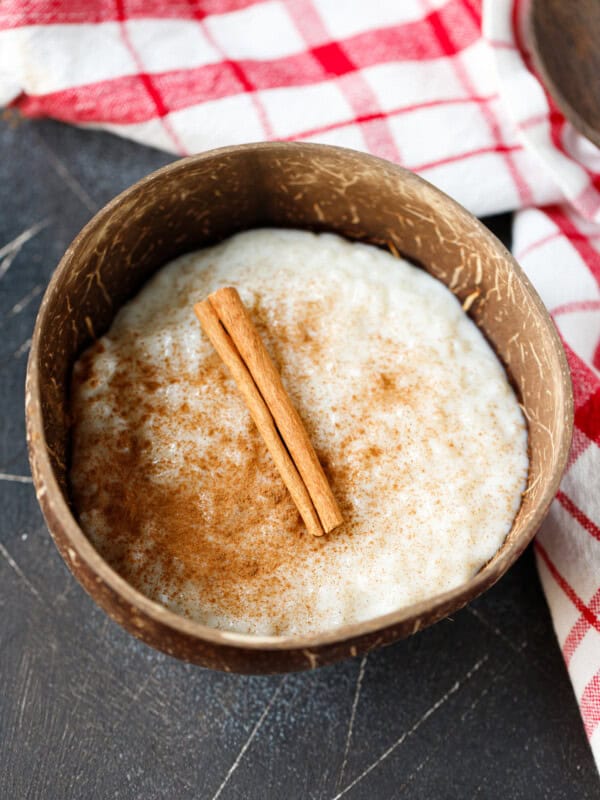 Classic rice pudding served in a rustic bowl dusted with cinnamon and topped with a cinnamon stick.