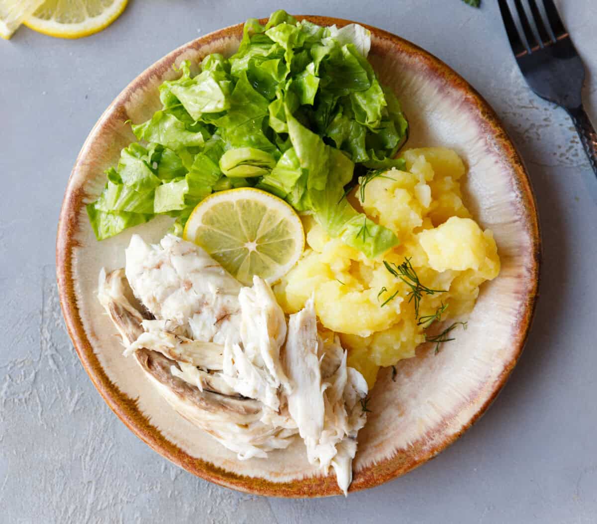 Serving plate with flaked roasted milokopi fish, boiled potatoes with dill, and fresh chopped lettuce.
