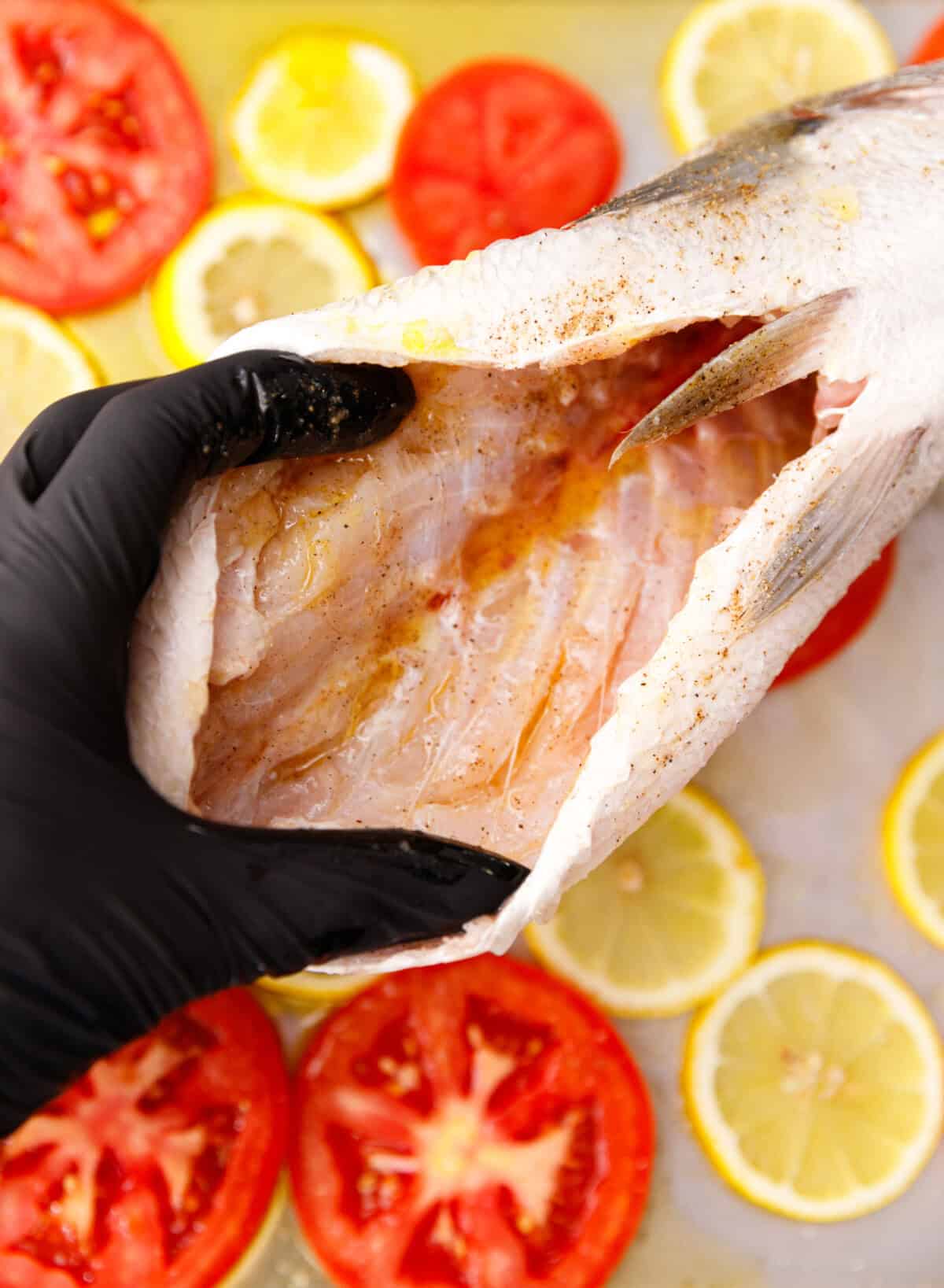 Seasoning the cleaned inside of the milokopi fish with salt, pepper, and olive oil.