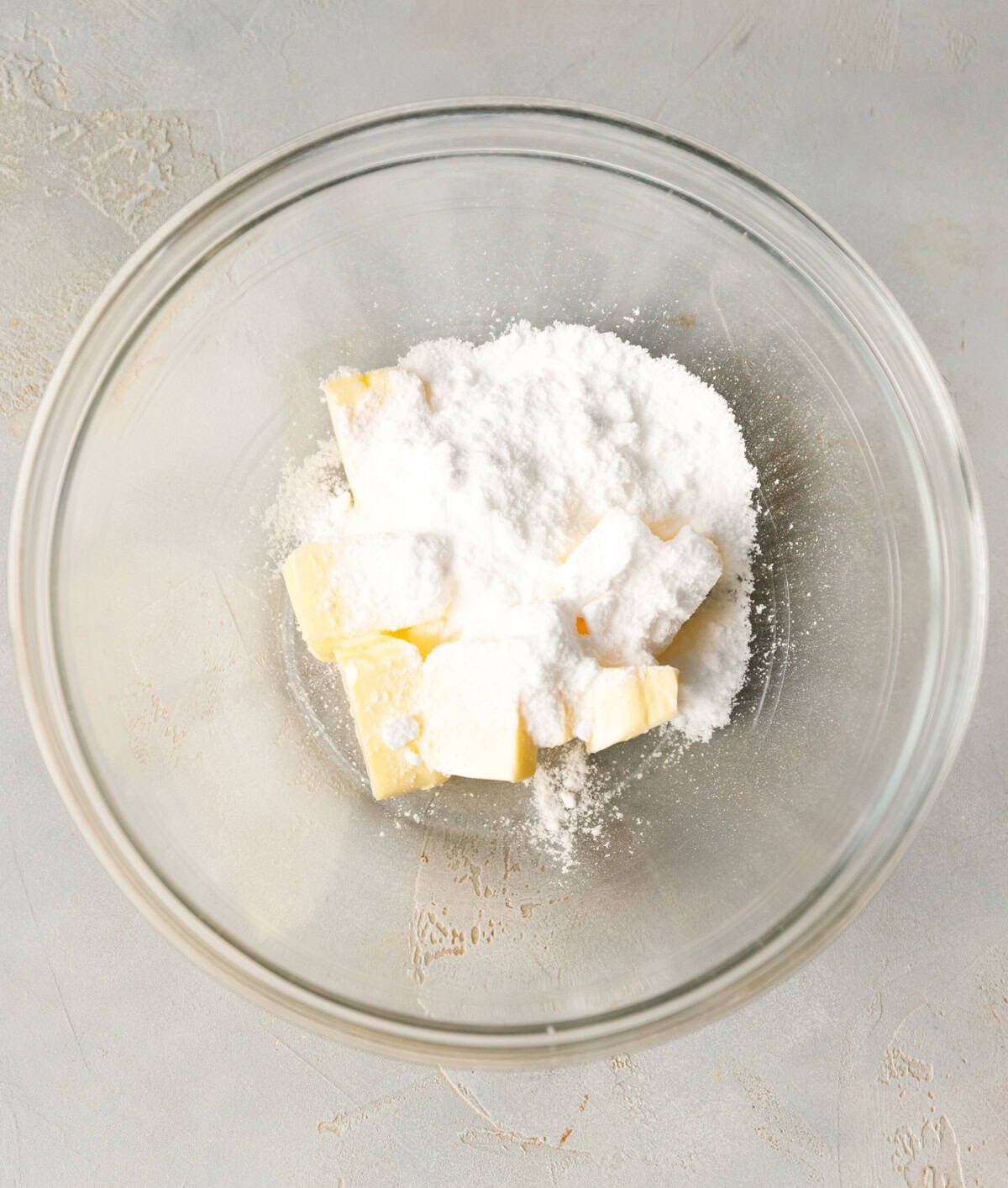 Cubed butter and powdered erythritol in a glass bowl before mixing.