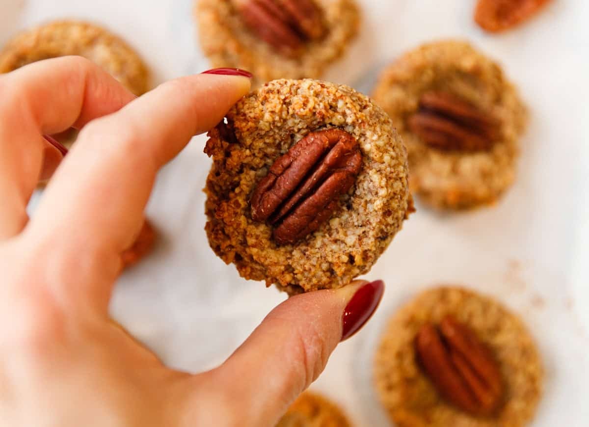 Hand holding a maple pecan cookie to show its texture and pecan topping