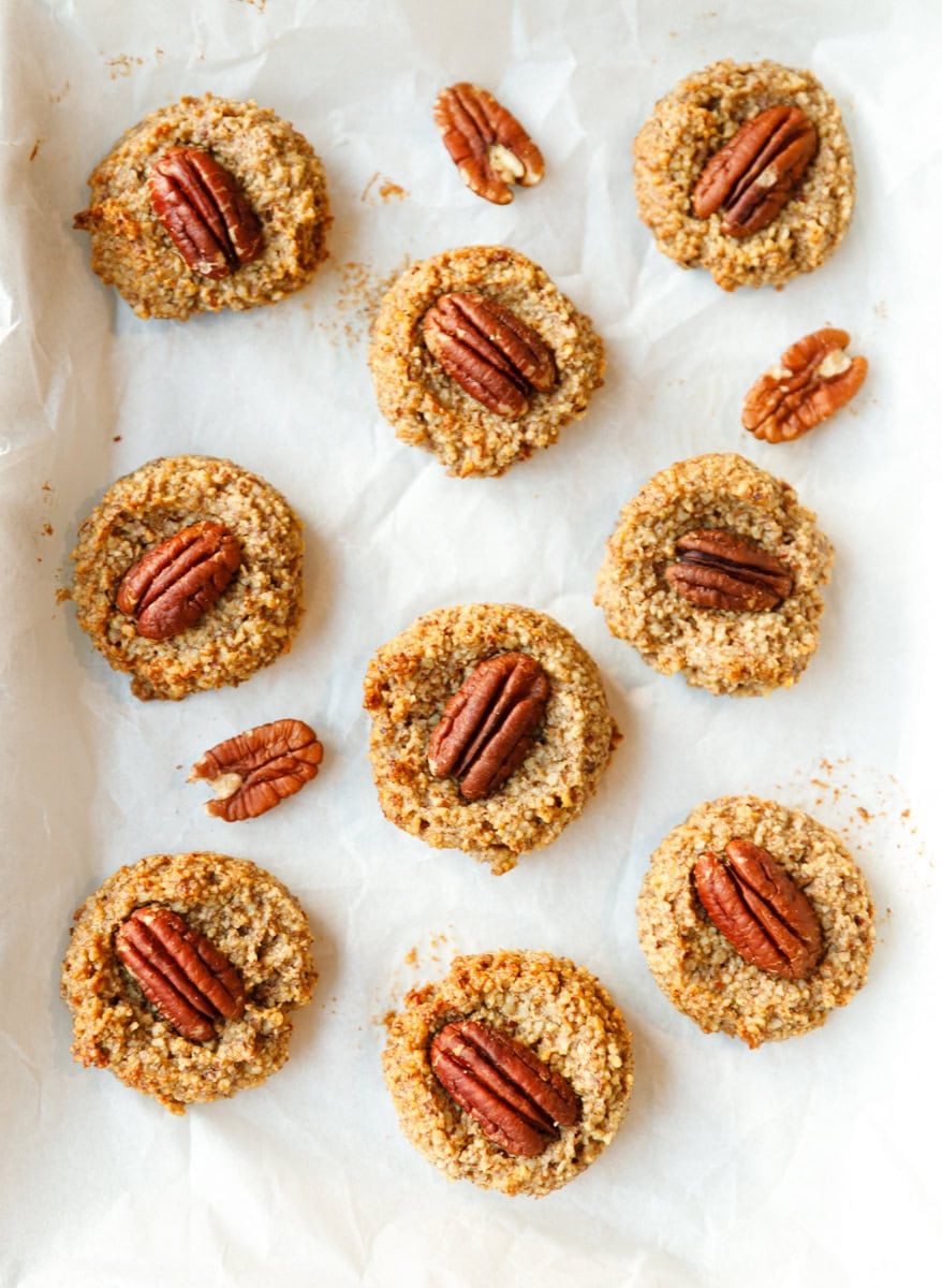 Overhead view of unbaked maple pecan cookies with pecan halves scattered on parchment