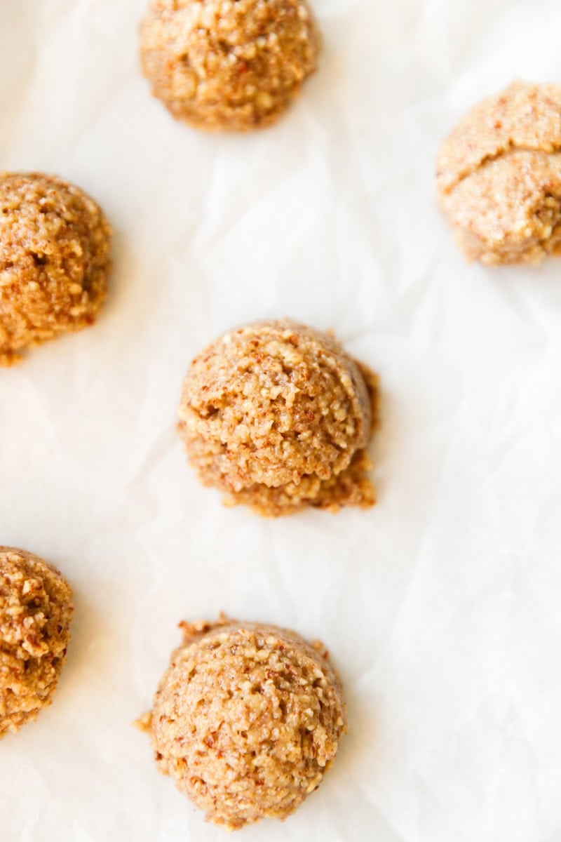 Scoops of unbaked maple pecan cookie dough arranged on parchment paper