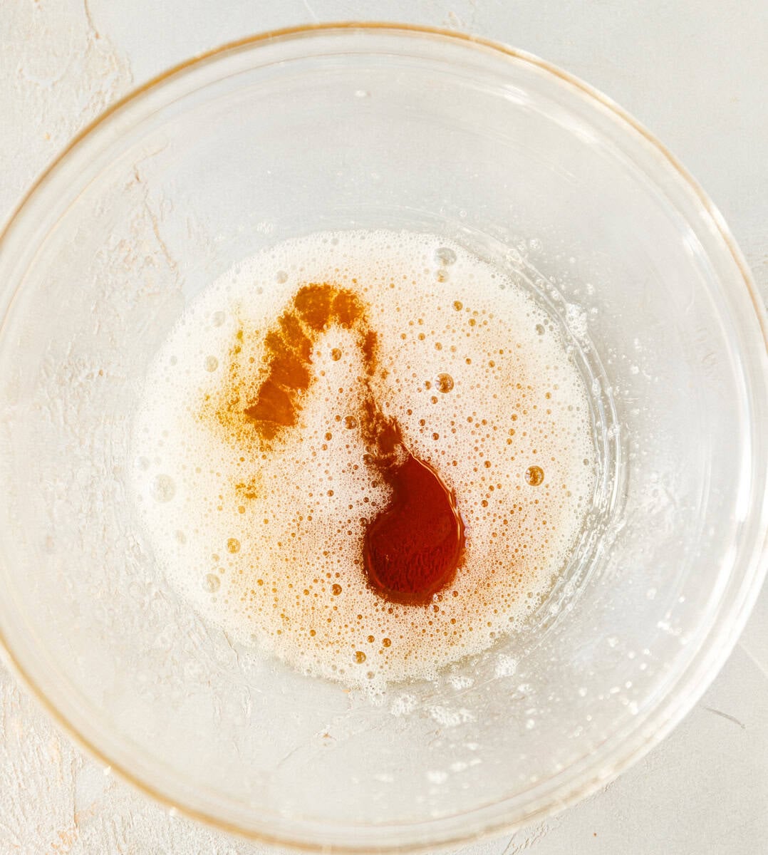 Egg white mixed with maple syrup in a clear bowl for three ingredient maple pecan cookies