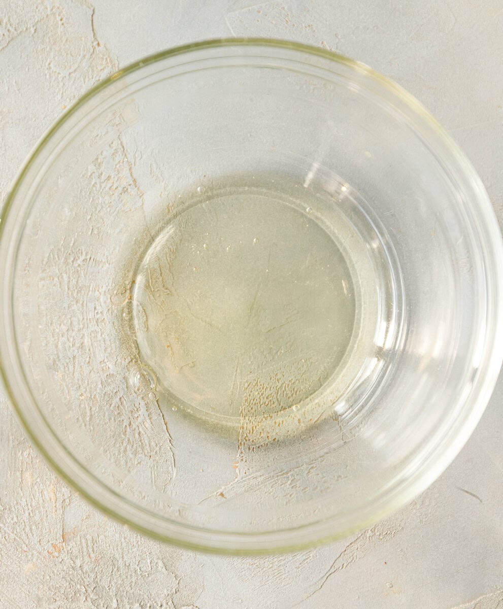 Plain egg white in a clear bowl ready to be whisked for maple pecan cookies