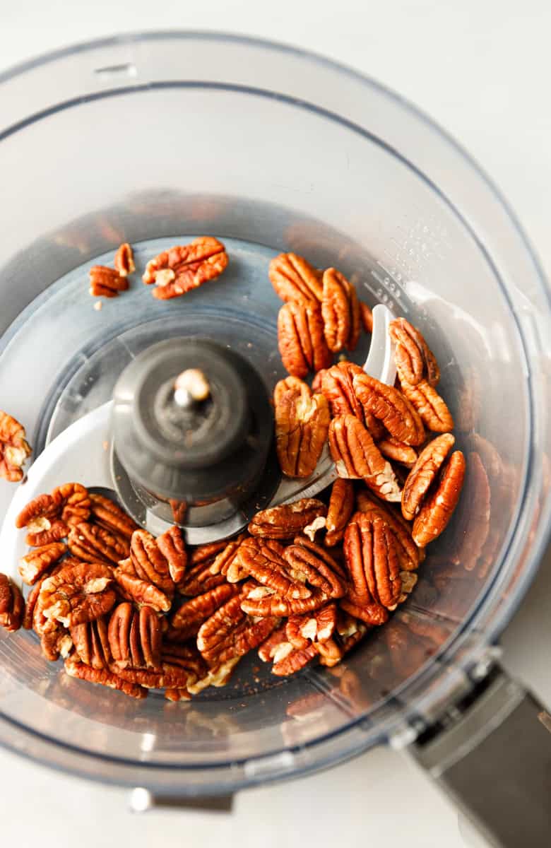 Whole raw pecans inside a food processor before grinding