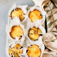 Savory cottage cheese egg muffins baked in a metal muffin tin, lined with parchment paper and topped with mixed seeds.