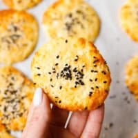 Low-carb cottage cheese flatbread topped with sesame seeds, held in hand, golden and lightly crisp