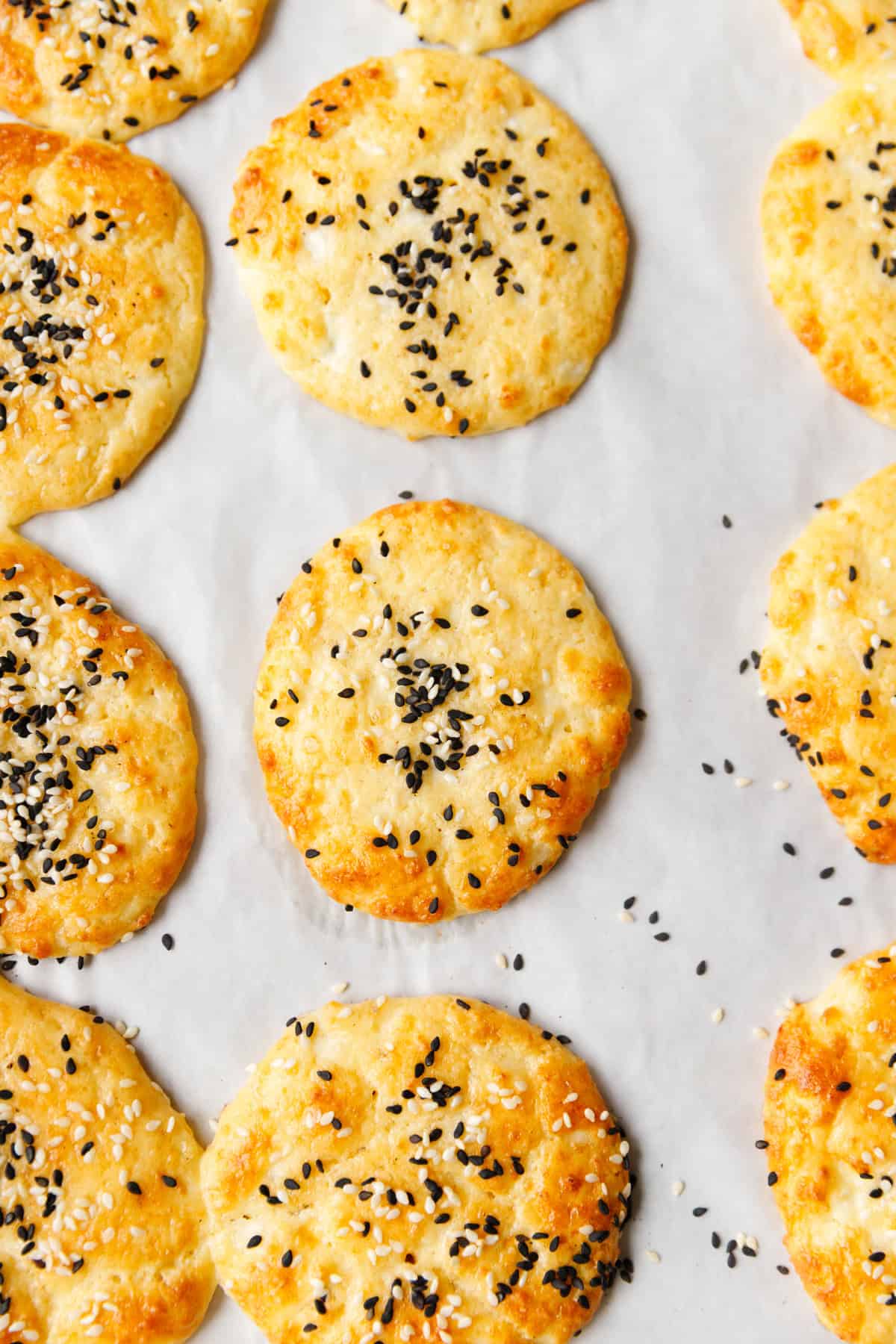 Freshly baked low-carb cottage cheese flatbreads with sesame seeds on parchment paper

