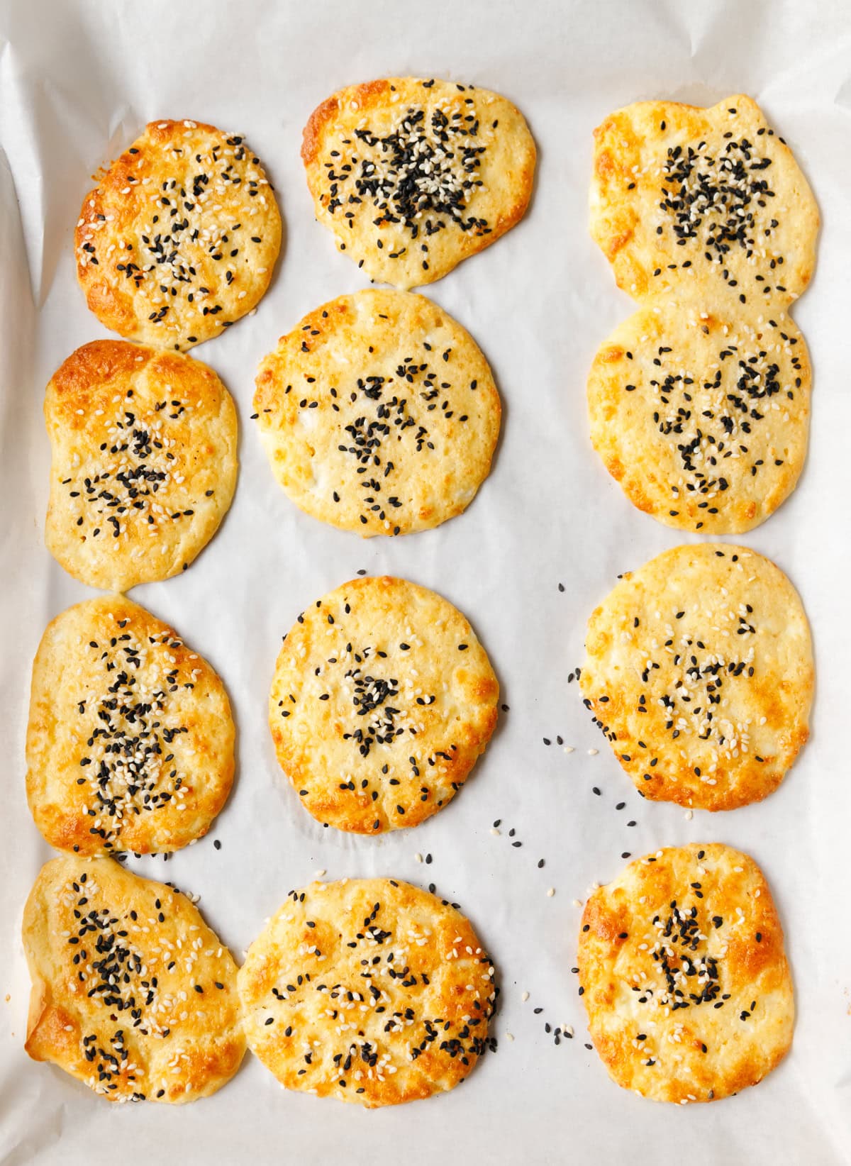 Low-carb cottage cheese flatbreads arranged on a baking sheet with sesame seeds