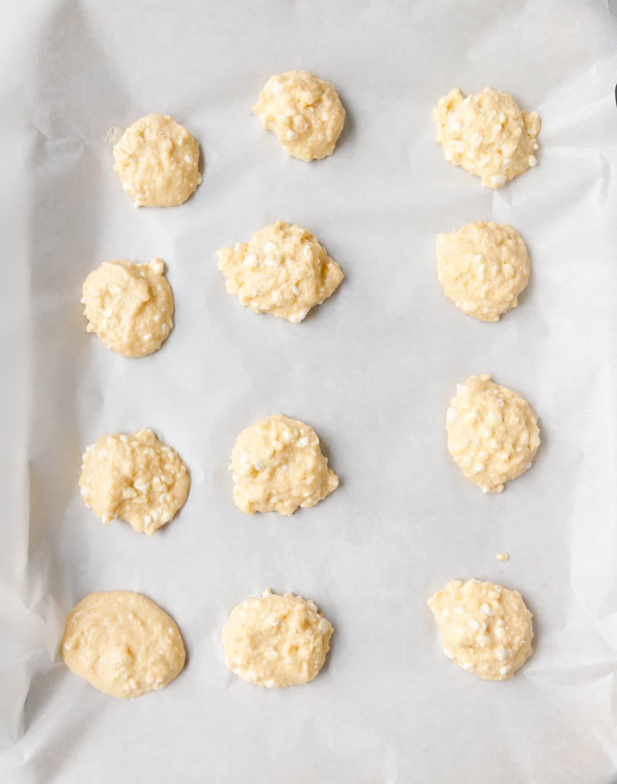 Portions of low-carb cottage cheese flatbread batter on parchment paper