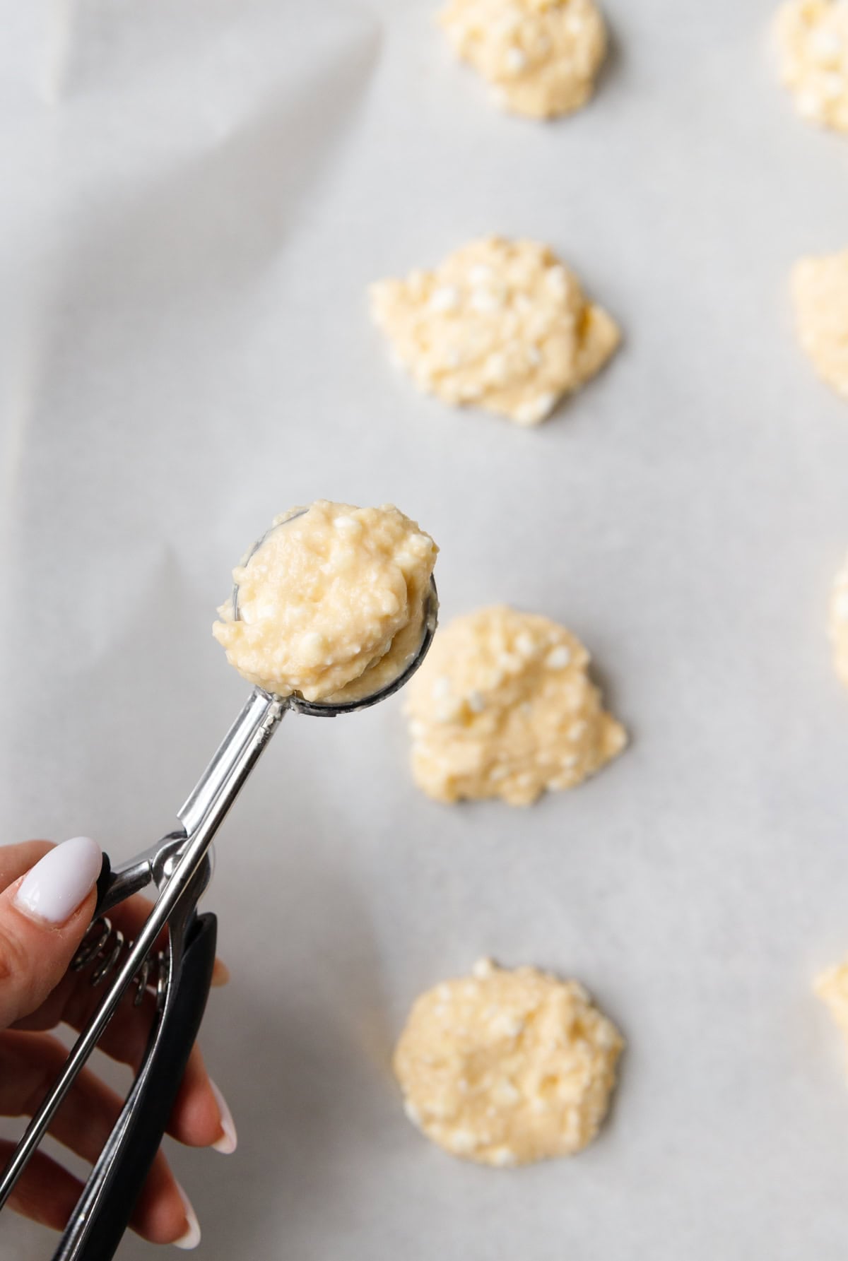 Scooping low-carb cottage cheese flatbread batter onto parchment paper