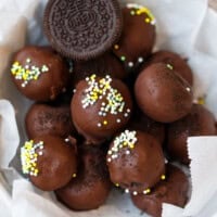 Chocolate Oreo truffles coated in dark chocolate with sprinkles in a white bowl