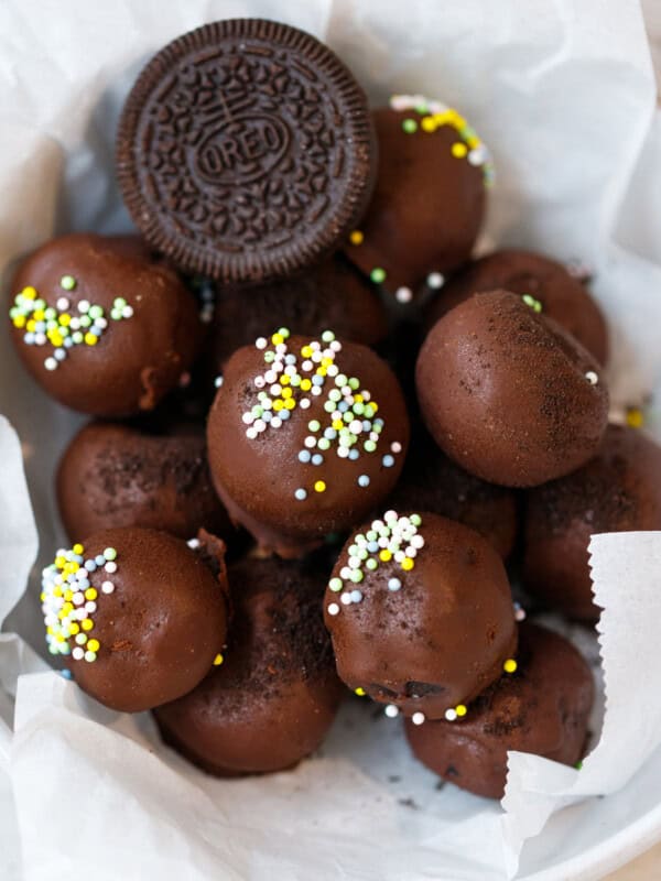 Chocolate Oreo truffles coated in dark chocolate with sprinkles in a white bowl