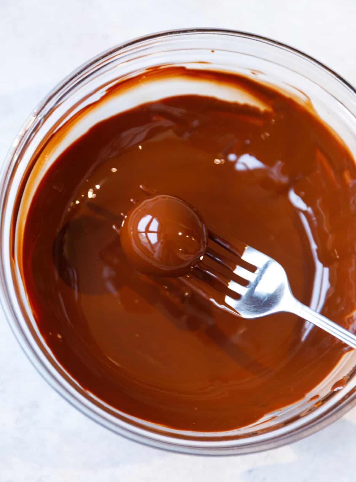 Oreo truffle being dipped in melted chocolate using a fork