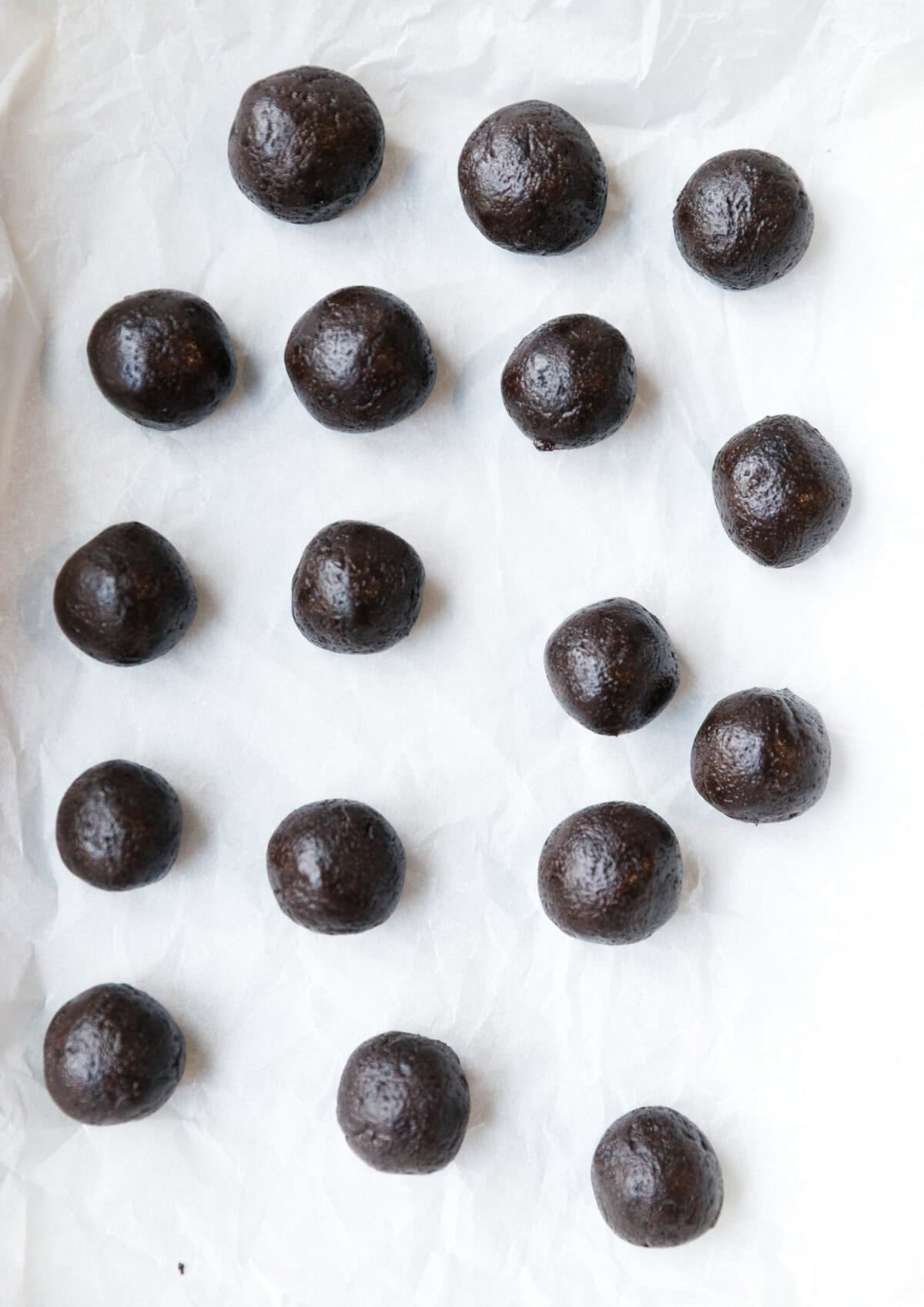 Oreo truffle balls placed on parchment paper before dipping