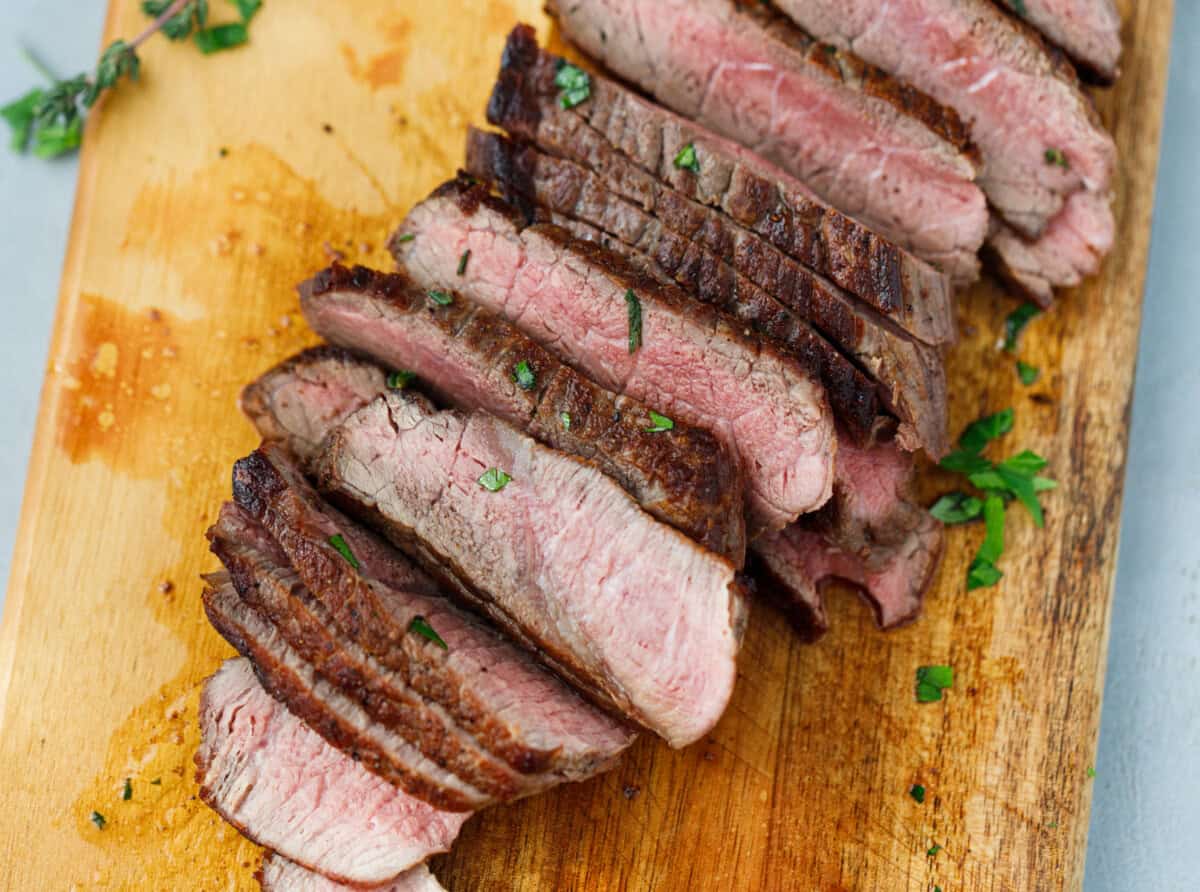 Denver steak sliced and garnished with chopped parsley and thyme.