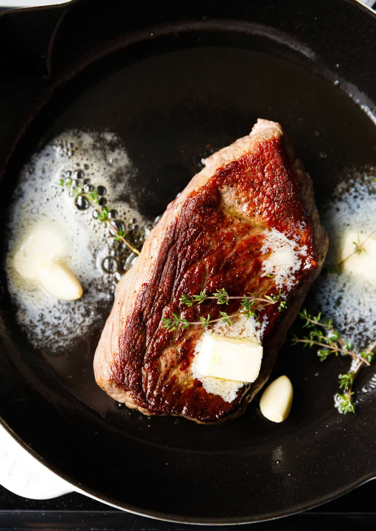 Denver beef steak inside a cast iron skillet with butter and thyme