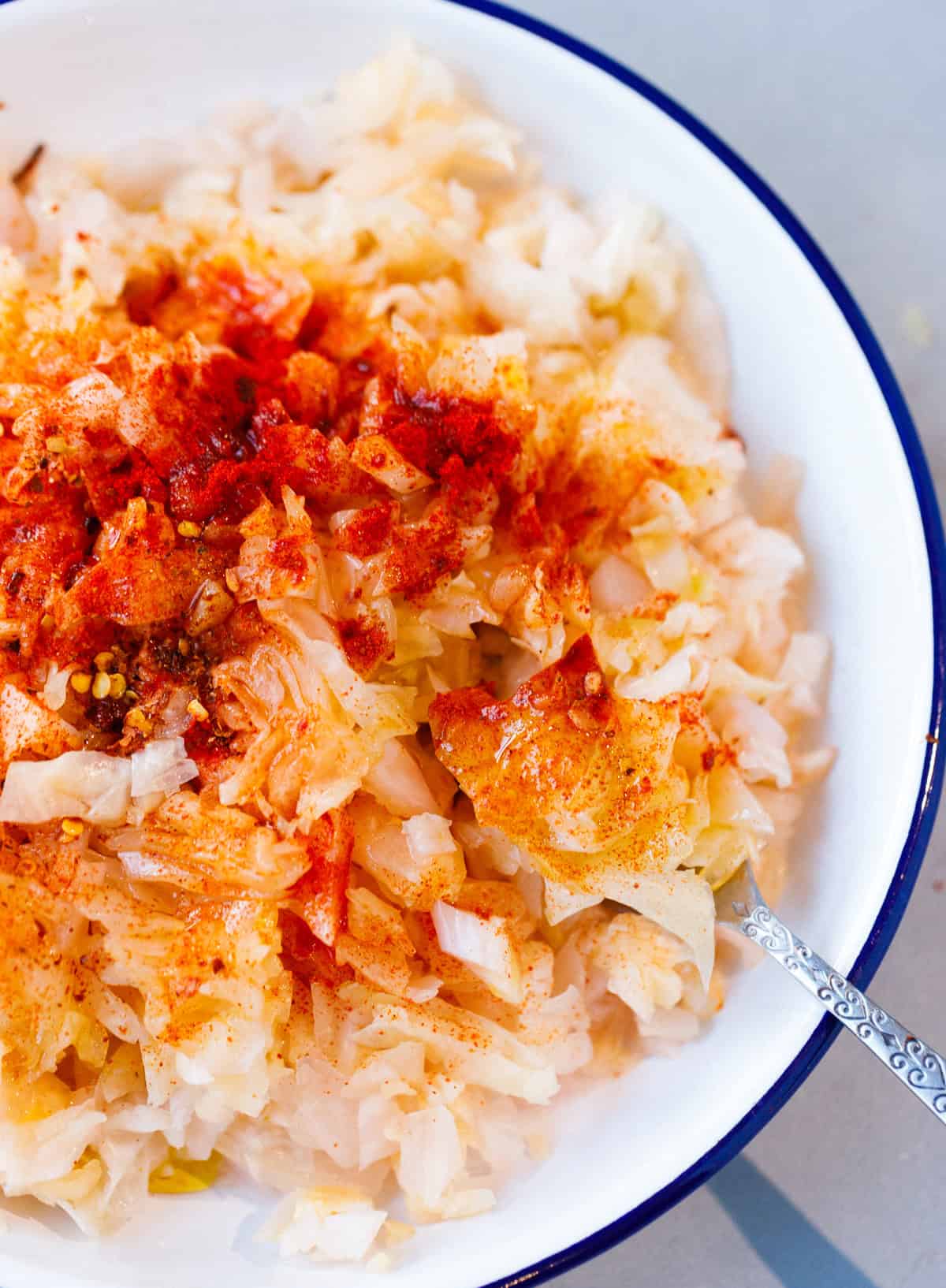 Bulgarian sauerkraut salad with fermented cabbage, olive oil, paprika, and chili flakes in a white bowl