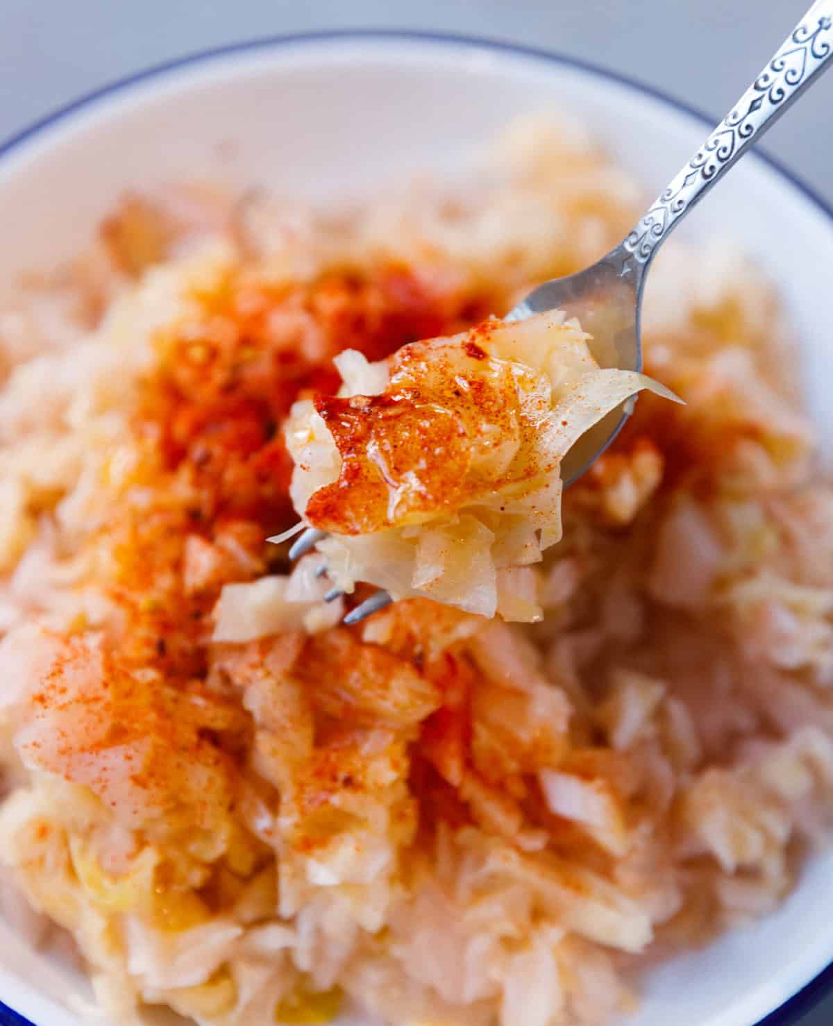 Fork lifting raw fermented sauerkraut salad seasoned with paprika and olive oil