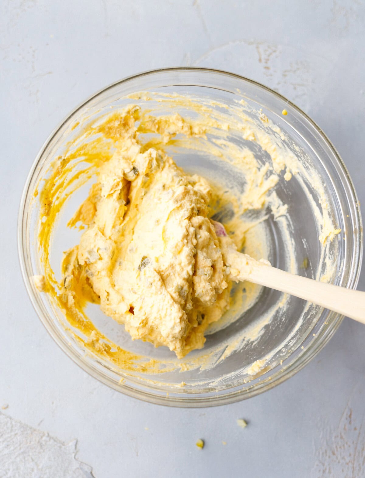 Creamy deviled egg filling mixed with pickles in bowl