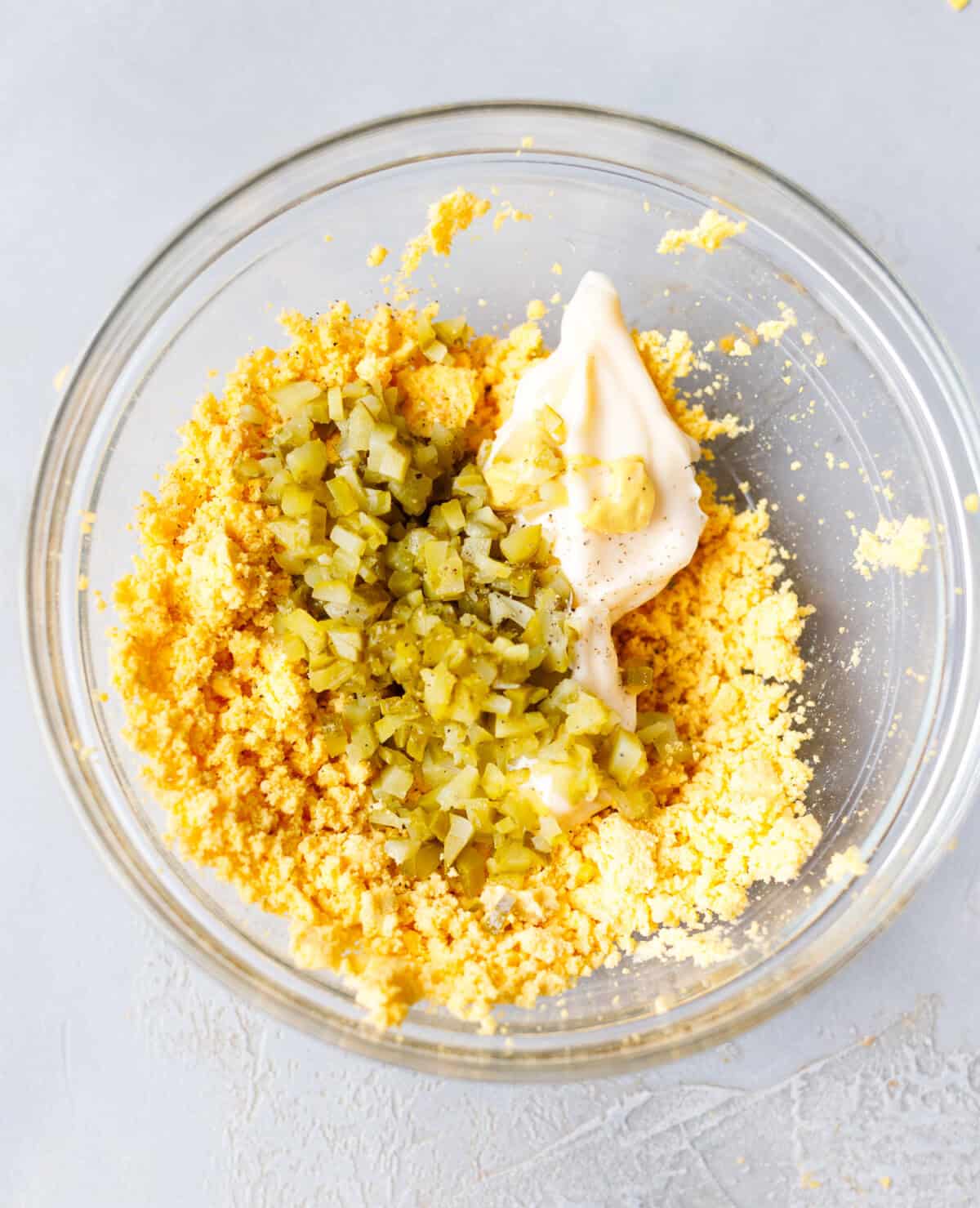Egg yolks mixed with mayonnaise and pickles for deviled egg filling