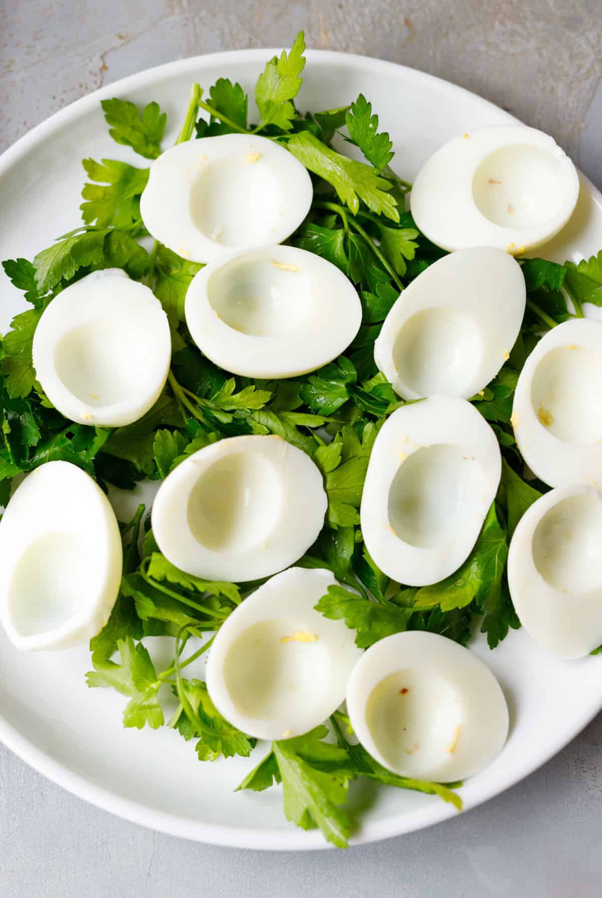 Halved egg whites arranged on parsley ready for deviled eggs