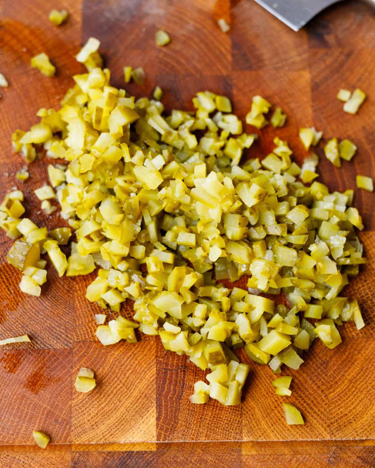 Finely chopped pickles on wooden cutting board for deviled egg filling