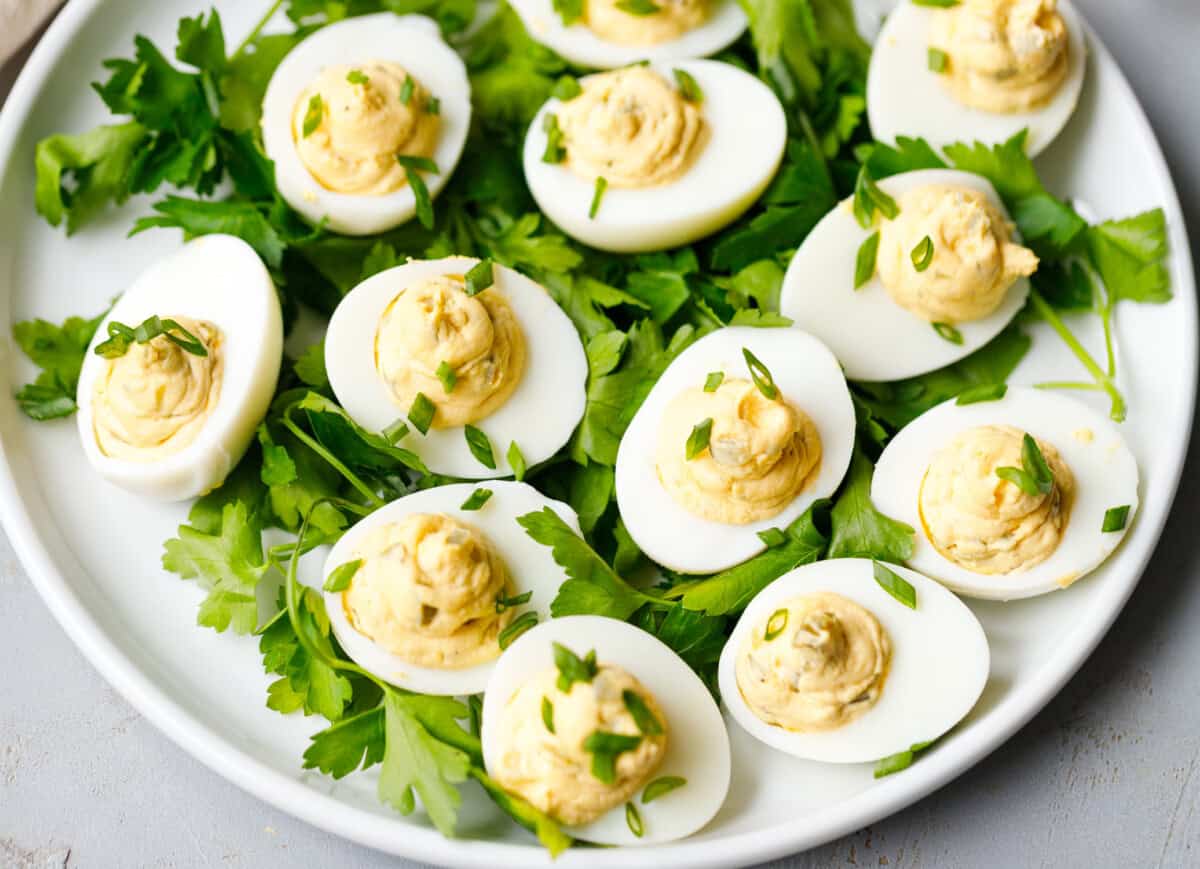 Close up of deviled eggs with smooth creamy filling and chopped herbs