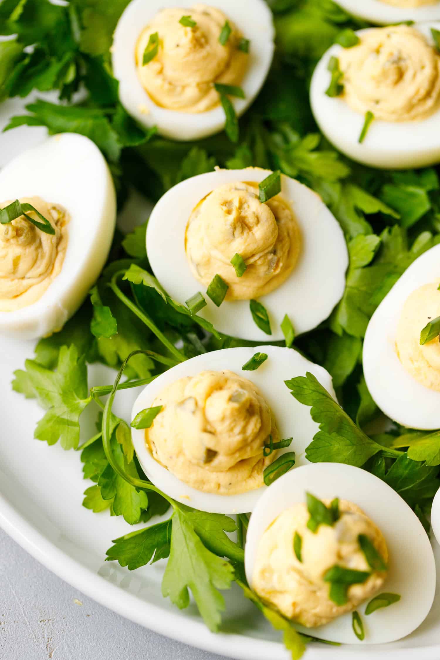 Deviled eggs with pickle filling garnished with green onions on parsley