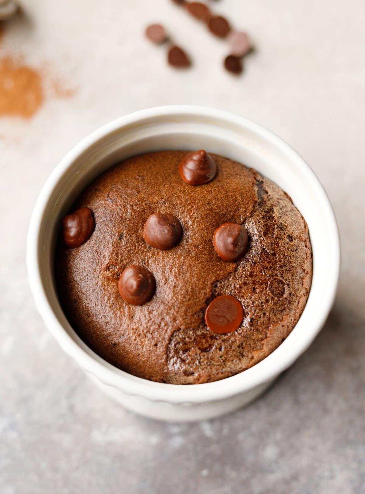 Low-carb chocolate collagen mug cake baked in a white ramekin with chocolate chips on top