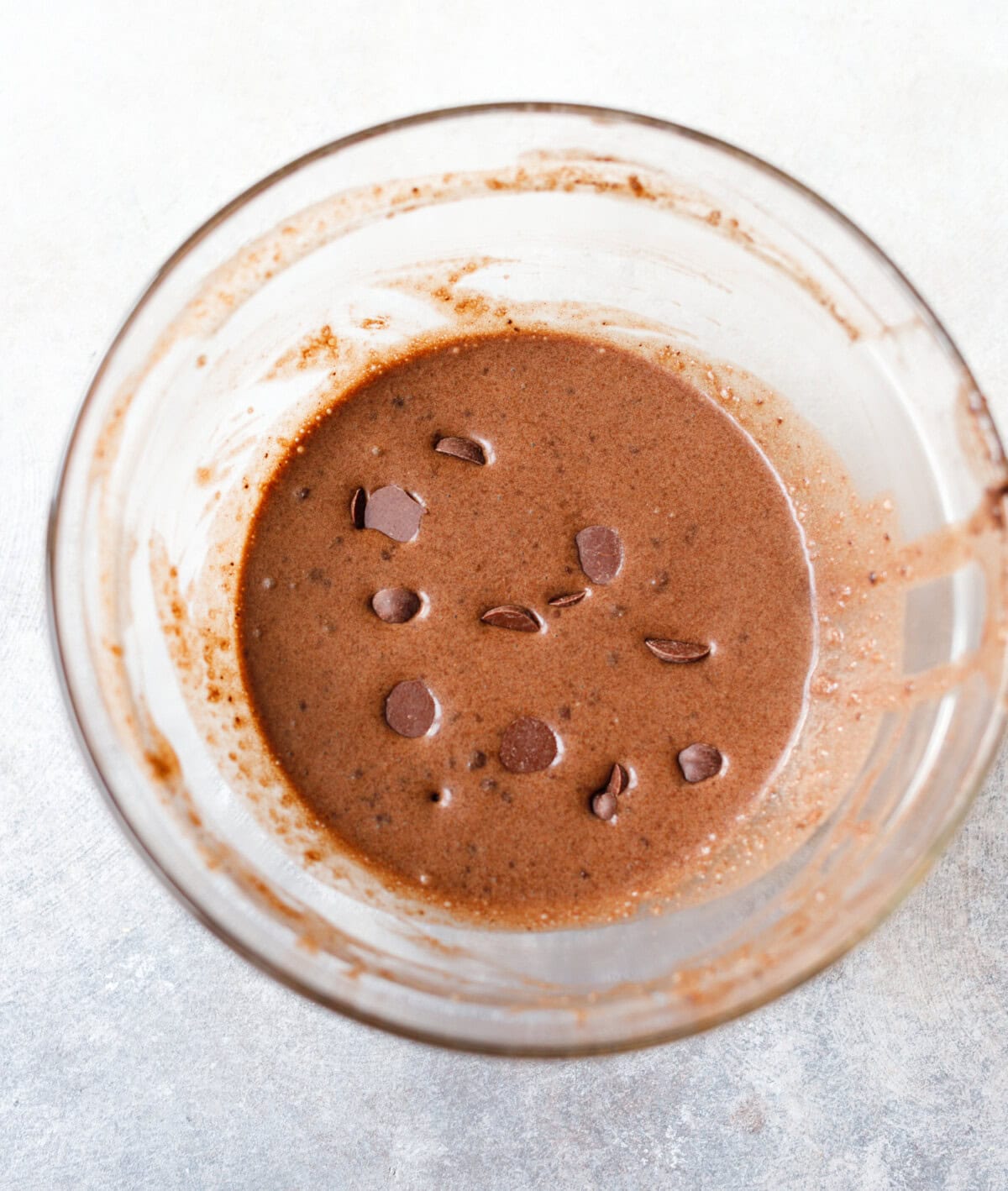 Chocolate cake batter with collagen and chocolate chips in a glass mixing bowl